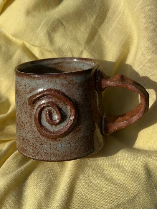 Light blue and brown mug with a raw clay spiral and handle.