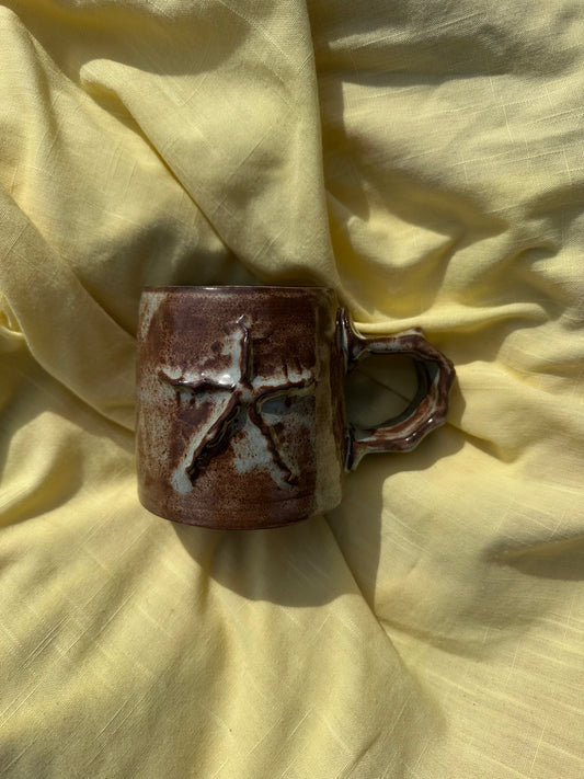 Brown ceramic mug with a textured star design.