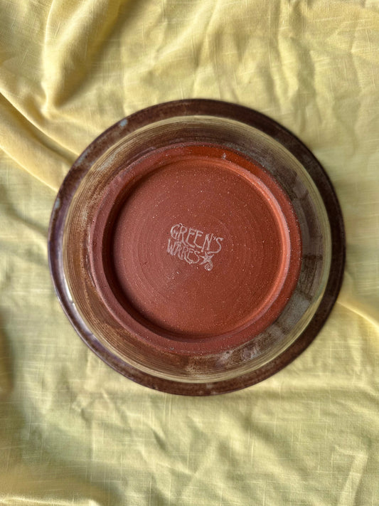Bottom of a ceramic bowl with red clay and "Green's Wares" branded stamp in the center.