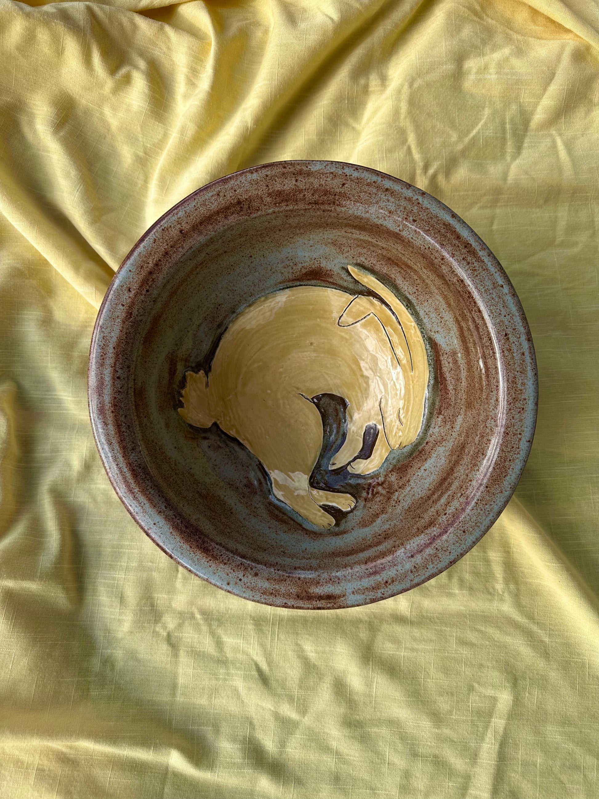 Large ceramic bowl with light blue and brown glaze and a sleeping bunny design in the center.