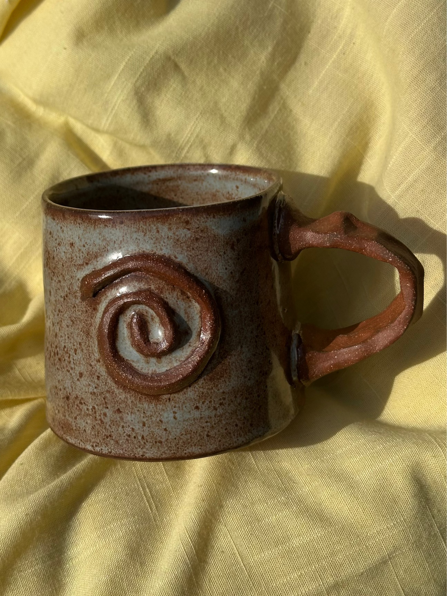Light blue and brown mug with a raw clay spiral and handle.